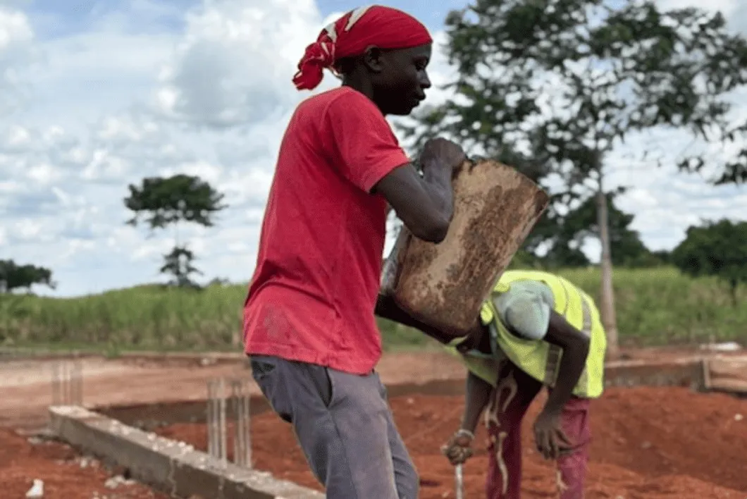 Workers carrying stones at the building site of the new building